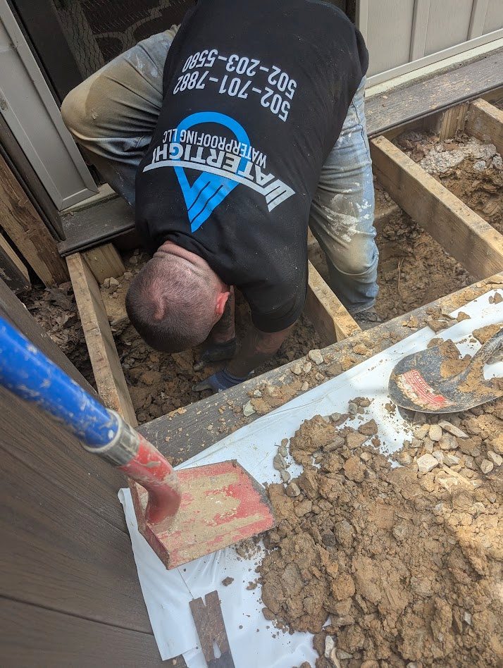 A worker reaching into an opening under a deck