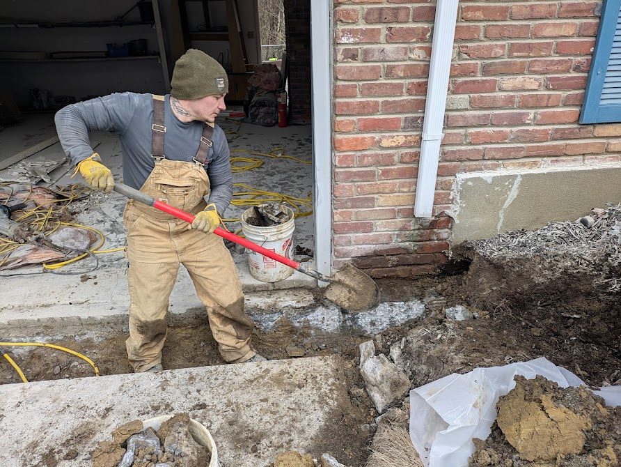 Worker digging near garage threshold