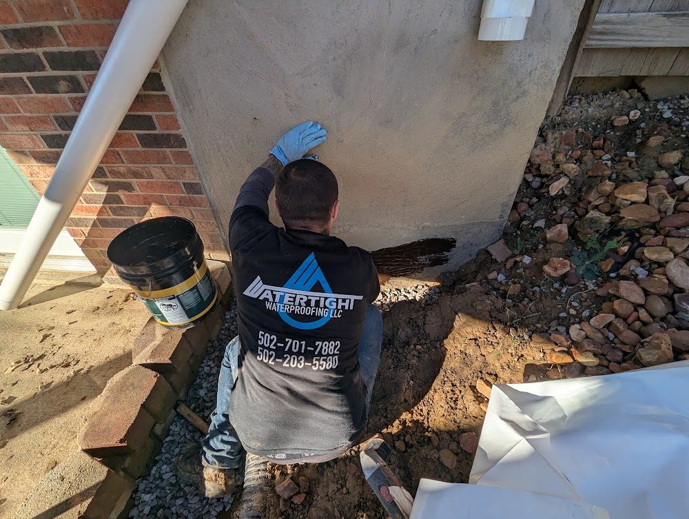 Worker applying material to foundation wall