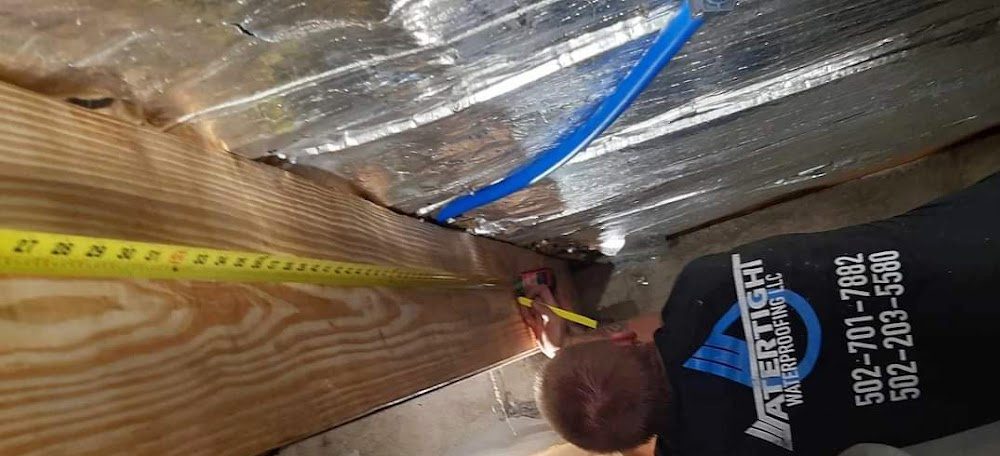 Worker measuring beneath floor framing