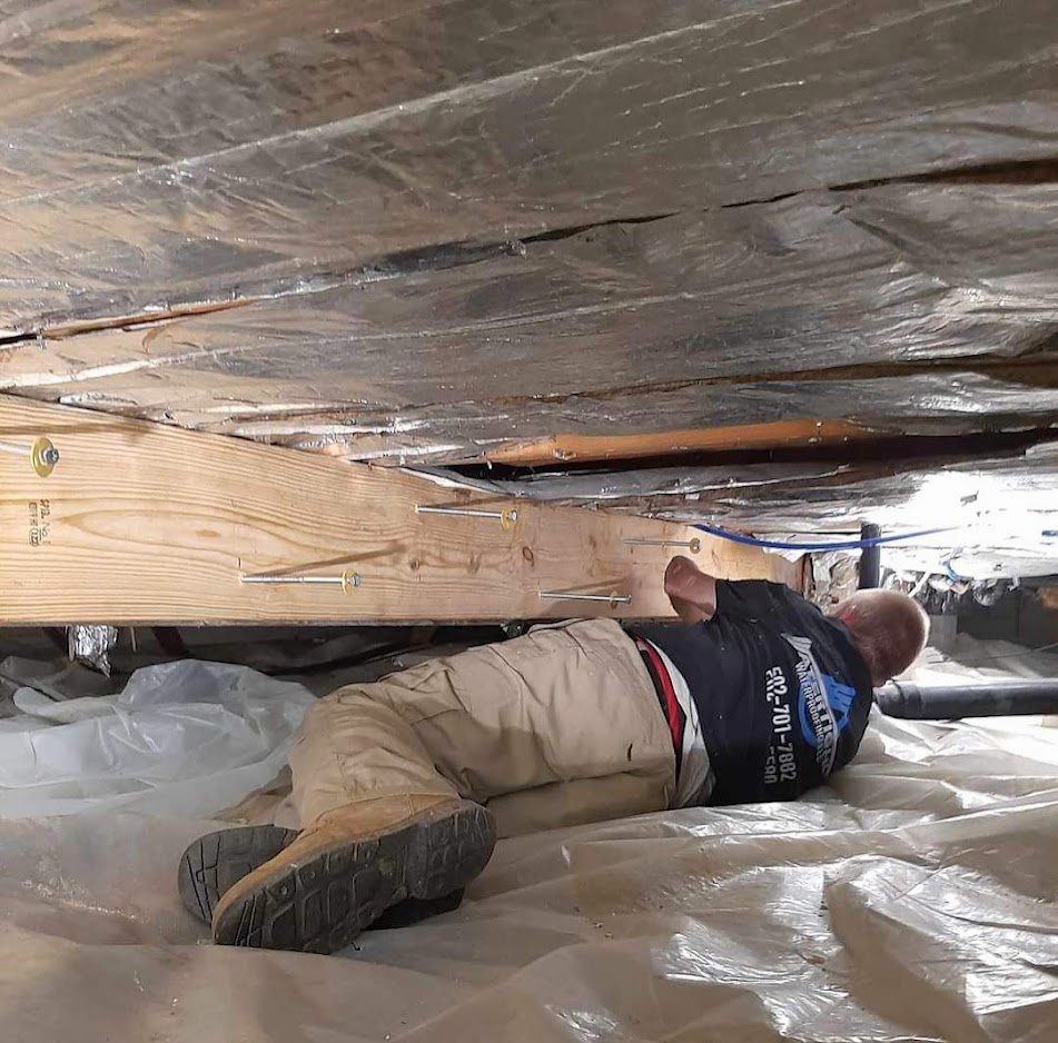 Worker beneath floor measuring framing