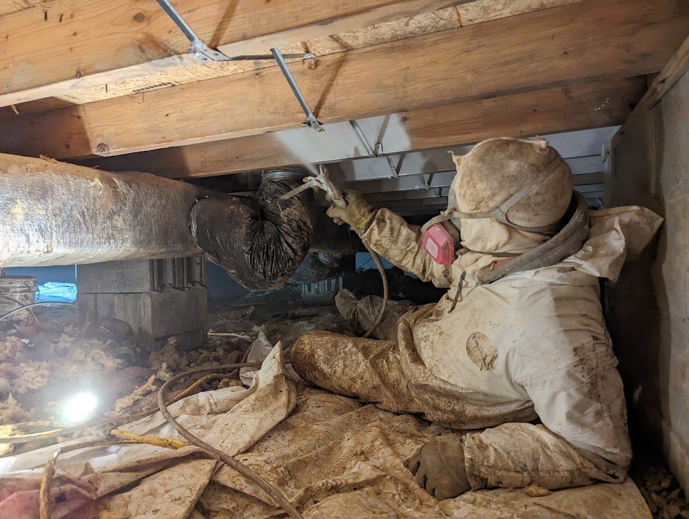 Worker in coveralls and respirator treating joists