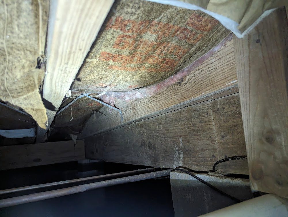 Looking up into a joist bay with the insulation pulled back