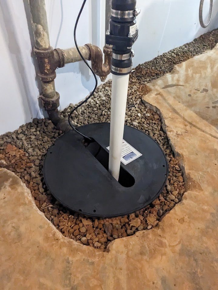 Sump cover and pipe beside gravel opening