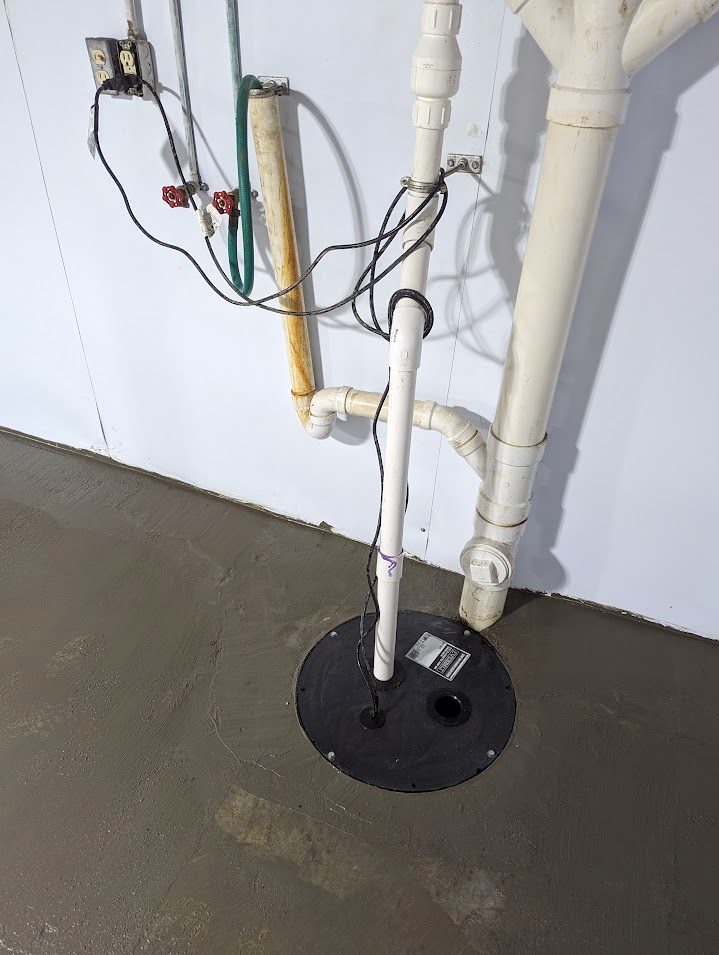 Sealed sump lid and discharge pipe against a lined basement wall