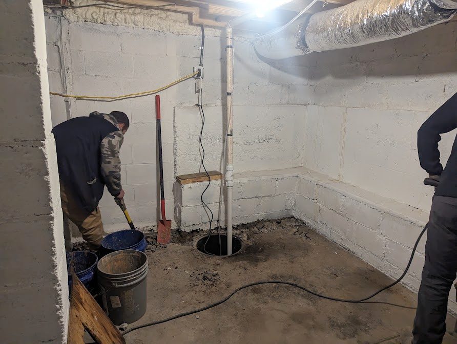 Worker beside open sump hole in basement