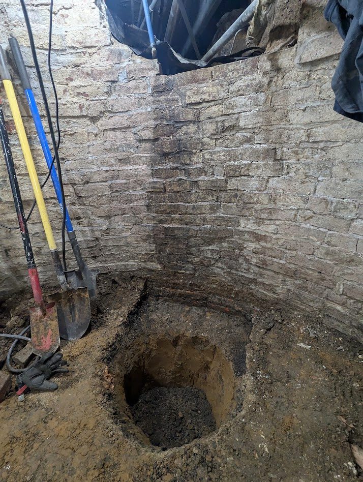 Deep circular hole beside basement wall